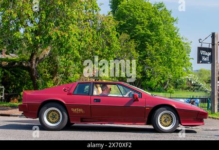 Stoke Goldington, Regno Unito - 11 maggio 2024: Auto d'epoca 1986 Maroon Lotus Esprit che viaggia attraverso un villaggio inglese Foto Stock