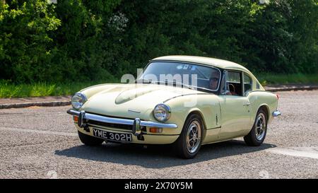 Stoke Goldington, Regno Unito - 11 maggio 2024: 1970 auto Triumph GT6 gialla che guida su una strada britannica Foto Stock