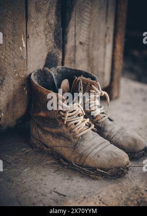 Stivali isolati fangosi da fattoria. Primo piano di un paio di stivali in pelle indossati con fango. Un aspetto rétro per il lavoro rurale Foto Stock