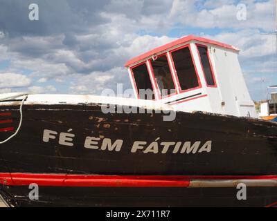 Barca in legno di colore bianco e rosso Fé em Fátima sullo scalo al porto di Fuseta, Algarve, Portogallo. Il nome è un titolo cattolico di Maria madre di Gesù Foto Stock