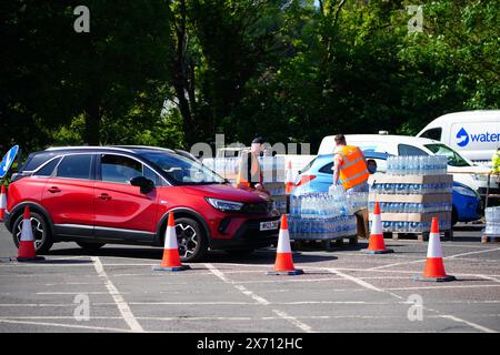 Persone che raccolgono acqua in bottiglia al Broadsands Car Park di Paignton. A circa 16.000 famiglie e aziende nell'area di Brixham nel Devon è stato detto di non usare l'acqua di rubinetto per bere senza prima bollirla e raffreddarla, a seguito della scoperta di piccole tracce di un parassita nella rete idrica locale. Data foto: Venerdì 17 maggio 2024. Foto Stock