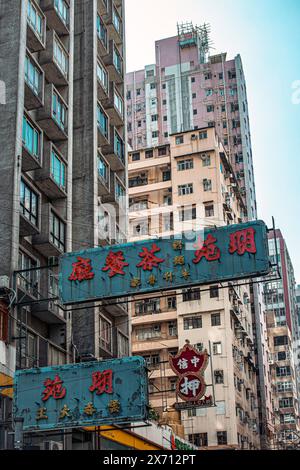 Una delle innumerevoli strade trafficate di Hong Kong che mostra i cartelli che pendono sopra la testa. Hong Kong, Cina, Asia. Foto Stock