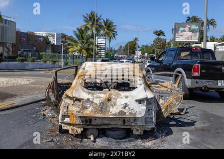 Resti di auto bruciate e altri atti vandalici compiuti dai rivoltosi durante la prima notte di terrore all'ingresso della rotonda AS De Trefle in Magenta. Sullo sfondo, si può vedere un'enorme folla di persone che cercano di accedere al mercato del Magenta, protetto dalle forze dell'ordine da qualsiasi saccheggio e vandalismo. Le tensioni sono rimaste alte a Noumea, la capitale della nuova Caledonia, venerdì dopo giorni di disordini, mentre il rappresentante del governo francese ha detto che le aree del territorio del Pacifico sono "fuggite" al controllo statale. Louis le Franc, alto commissario della Repubblica in nuova Caledonia, ha annunciato il nuovo secur Foto Stock