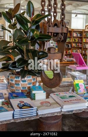 La libreria all'interno di Salts Mill, Saltaire, Yorkshire. Un grande gancio, parte del macchinario originale del mulino, è appeso al soffitto. Foto Stock