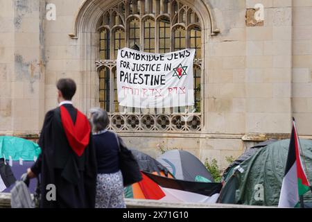 Gli studenti laureati si trovano vicino a una protesta dell'accampamento per il conflitto di Gaza sui terreni dell'Università di Cambridge. Le cerimonie di laurea sono state spostate a causa del campo di protesta pro-Palestina. Data foto: Venerdì 17 maggio 2024. Foto Stock