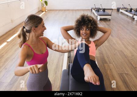 In studio, istruttrice caucasica che aiuta la donna birazziale Foto Stock