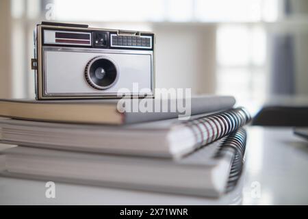 Una macchina fotografica d'epoca si siede su un tavolo in un ufficio e un libro si distingue sullo sfondo. Una videocamera vintage dal design semplice si trova su un tavolo Foto Stock