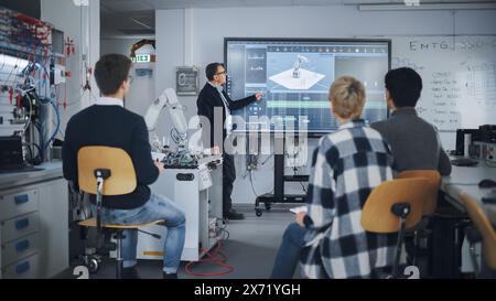 Insegnante che punta sul grande schermo e tiene in mano la lezione mentre il braccio robotico si muove nelle vicinanze. Gruppo diversificato di giovani ingegneri seduti all'università e chiedendo. Concetto di educazione informatica Foto Stock