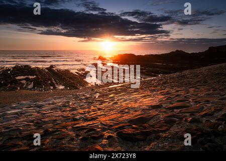 Un intenso tramonto sulla spiaggia di Breakwater sulla costa di Bude in Cornovaglia nel Regno Unito. Foto Stock