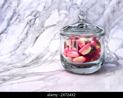 Vista laterale di un vaso di vetro trasparente riempito di dolci multicolore , senza etichetta con spazio di copia Foto Stock