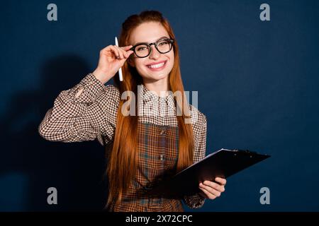 Foto di un vestito a quadri allegro e carino che firma un contratto con uno spazio vuoto, sfondo blu scuro isolato Foto Stock