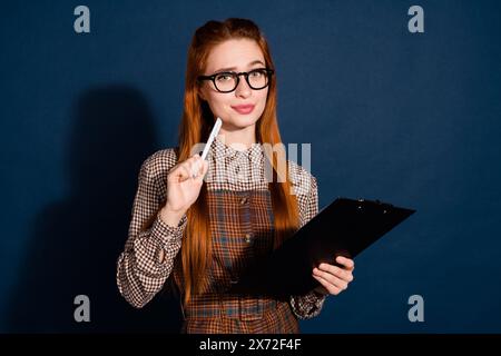 Foto di un abito a quadri con dubbio dubbio dubbio dubbio dubbio, firmato da una signora, che firma un contratto, sfondo blu scuro isolato Foto Stock