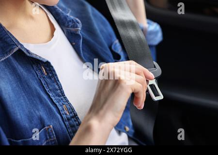 Donna che indossa la cintura di sicurezza all'interno di un'auto moderna Foto Stock