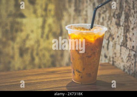 tè tailandese al latte freddo in tazza di plastica con ghiaccio e cannuccia Foto Stock