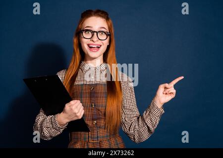 Foto di un vestito a quadri decorato da donna con appunti che punta a uno spazio vuoto con sfondo blu scuro isolato Foto Stock