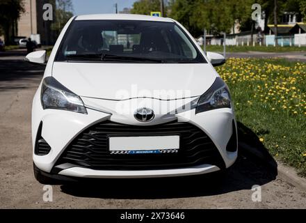 Minsk, Bielorussia, 17 maggio 2024 - Toyota Yaris bianca è parcheggiata sulla strada. Vista laterale anteriore. Foto Stock