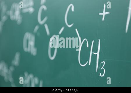 Formule chimiche scritte con gesso sul bordo verde, primo piano Foto Stock