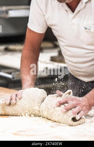 Un panettiere impasta l'impasto nel forno. Verticale. Foto Stock