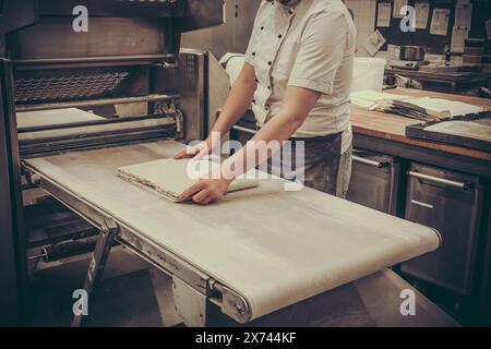 Macchina automatica per impastare l'impasto per preparare la pasta sfoglia. Processo di preparazione dei croissant francesi. Foto Stock