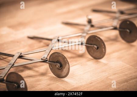 Taglierina professionale a più ruote per impasti, pizza, croissant, su un tavolo di legno, stile vintage Foto Stock