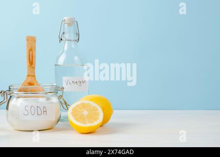 Aprire il vaso di bicarbonato con un cucchiaio di legno sopra, aceto, limone tagliato su sfondo blu. Il concetto di rimozione organica delle macchie sui vestiti Foto Stock