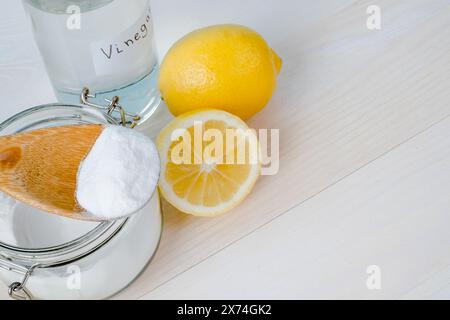 Aprire il vaso di bicarbonato con un cucchiaio di legno sopra, aceto e limone tagliato. vista dall'alto, spazio per il testo. Il concetto di rimozione organica delle macchie sui vestiti Foto Stock