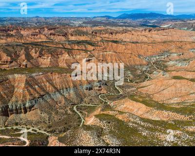 Ampio paesaggio desertico con rocce rosse e canyon, attraversati da serpenti, vista aerea, Los Coloraos, Grand Canyon dell'Andalusia, Gorafe dese Foto Stock