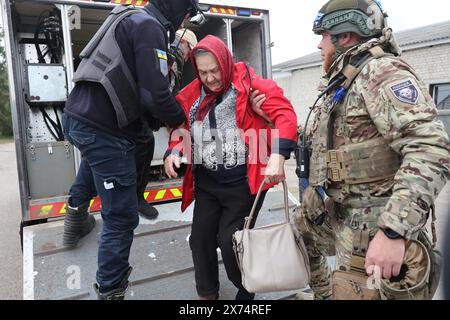 REGIONE DI CHARKIV, UCRAINA - 17 MAGGIO 2024 - Un ufficiale di polizia e un militare aiutano una donna anziana a scendere da una rampa durante l'evacuazione da Vovchansk, che è sotto costante bombardamento russo, regione di Charkiv, Ucraina nord-orientale. Foto Stock