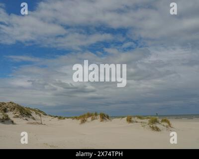 Ampio paesaggio di dune con sabbia ed erba sotto un cielo blu leggermente nuvoloso, dune con erba duna e una barca sul mare, nuvole sulla spiaggia, nes Foto Stock