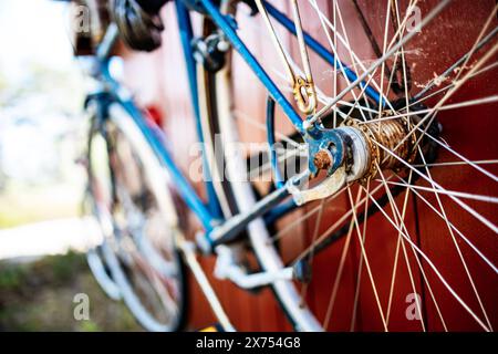 Antica bici blu ruggine appesa su un capannone rosso Foto Stock