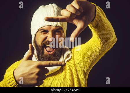 Il bell'uomo barbuto crea una cornice con le dita. Foto di selfie immaginarie. Insegna fotografica. Happy Guy mostra un gesto fotografico. Uomo barbuto che usa Foto Stock