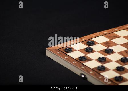 Scacchiera con dama. Concetto di gioco. Gioco da tavolo. Hobby. Dama sul campo di gioco per una partita. Su sfondo nero. Foto Stock