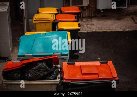 Cassonetti colorati e luminosi per la raccolta di rifiuti di vario genere in un cortile posteriore. Contenitori per rifiuti per la separazione di diversi tipi di materiali di scarto. Cestino. Foto Stock