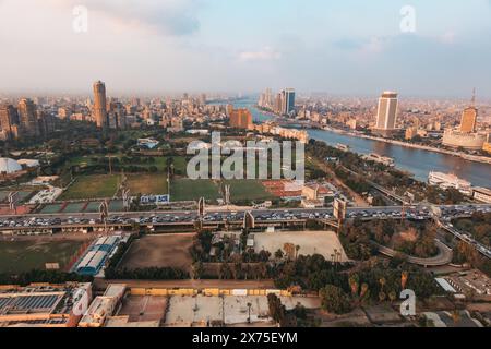 Vista aerea del Cairo con il Nilo, torri moderne, ponti e fitti edifici che si estendono per tutta la città, con parchi verdi in primo piano sotto. Foto Stock