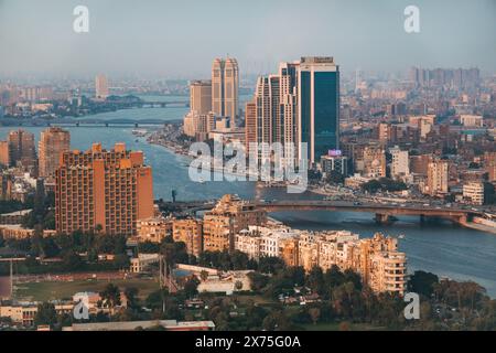 Vista aerea del centro del Cairo con il fiume Nilo che si snoda attraverso moderni grattacieli, ponti e edifici densamente affollati sotto la luce nebulosa del pomeriggio. Foto Stock