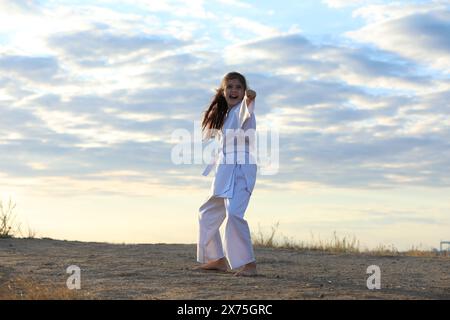 Carina bambina in kimono pratica karate all'aperto Foto Stock