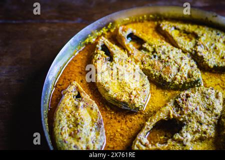 Sorshe ilish o hilsa curry di pesce cotto con semi di senape servito su un piatto. Pezzi di pesce sono visti in una ricca salsa gialla. Questo è un mestiere molto popolare Foto Stock