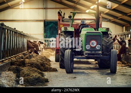 Azienda agricola, macchina e vecchio trattore in stalla con sporcizia, ruggine e polvere in magazzino a terra. Camion d'epoca, retrò e aratro in un capannone abbandonato Foto Stock