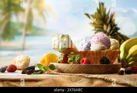 Gelato alla frutta assortito su un tavolo di legno sulla sabbia con sfondo tropicale Foto Stock