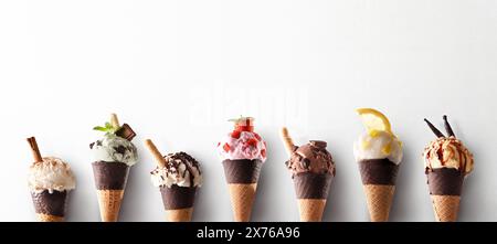 Assortimento di coni di gelato di vari gusti in fila con cono con cioccolato su sfondo bianco. Foto Stock