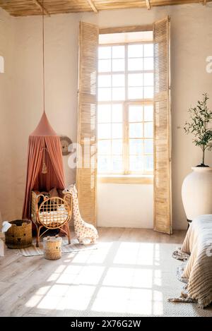 Camera per bambini in stile scandinavo, luminosa con letto, giocattoli e grande finestra con luce solare. mobili in legno. Foto Stock