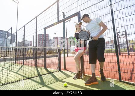 Allegra coppia atletica che ride durante la partita di tennis sul campo all'aperto. Foto Stock