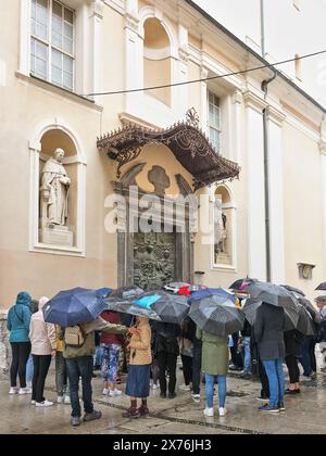 Gruppo di turisti con ombrelloni fuori dalla chiesa cattedrale di San Nicola, Lubiana, Slovenia, in una giornata umida. Foto Stock