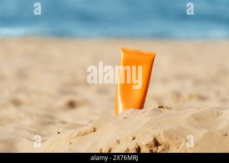 bottiglia di crema solare arancione sulla spiaggia sabbiosa Foto Stock