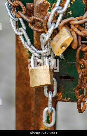 primo piano del lucchetto e delle catene sul cancello arrugginito Foto Stock