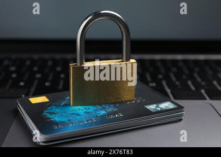 Sicurezza informatica. Lucchetto metallico e carte di credito sul laptop, primo piano Foto Stock