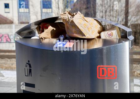 Augusta, Baviera, Germania - 25 febbraio 2024: Bidone di spazzatura in una stazione della Deutsche Bahn *** Überfüllter Mülleimer an einem Bahnhof der Deutschen Bahn Foto Stock