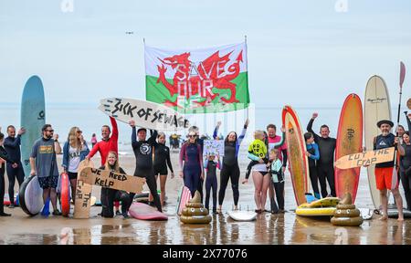 Le persone prendono parte a una pagaia a Caswell Bay a Swansea, parte di un evento nazionale organizzato dai surfisti contro le acque reflue, per chiedere la fine dell'inquinamento delle acque reflue e protestare contro le pratiche attuali di fognatura che entrano in mare. Foto Stock