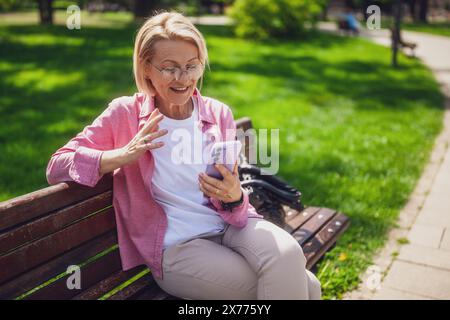 Ritratto di una donna matura nel parco. Sta parlando al telefono. Foto Stock