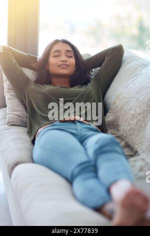 Casa, rilassati e donna sul divano, dormi e respira con il pisolino pomeridiano, occhi chiusi e calma nella sala. Appartamento, persona felice e ragazza sul divano Foto Stock